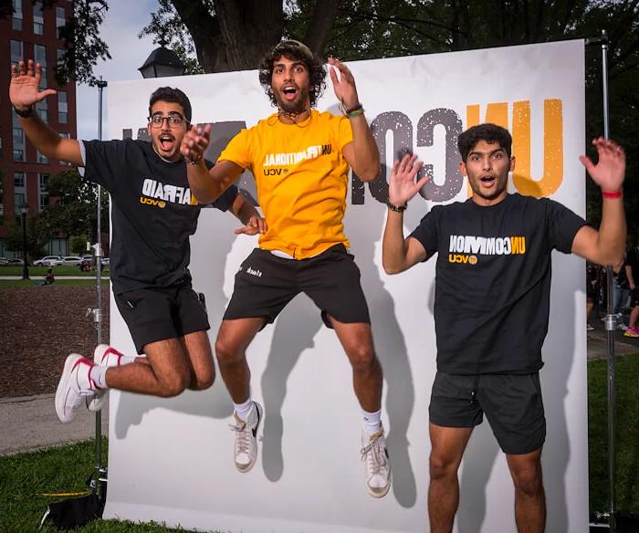 三个体育博彩的学生在空中跳跃
